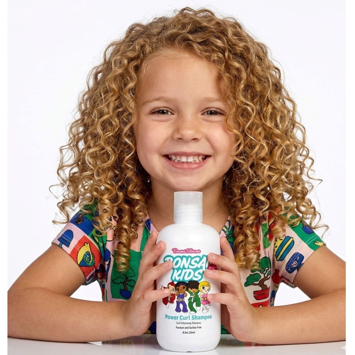 Child holding a bottle of Dona Kids Power Curl Shampoo against a white background