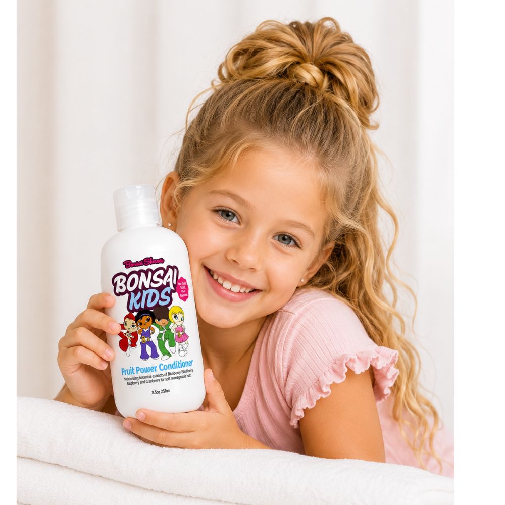 Young girl holding a bottle of Bonsai Kids fruit power conditioner against a white background