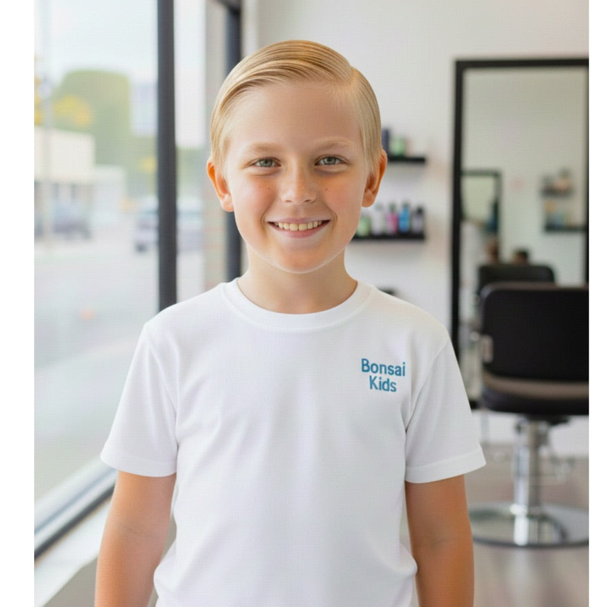 Young boy wearing a white t-shirt with 'Bonsai Kids' logo in a salon setting
