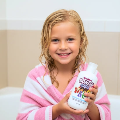 Child holding a bottle of BONZAI Kids shampoo, wrapped in a pink and white towel.